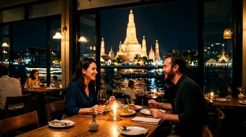 Couple dining riverside watching illuminated Wat Arun at night